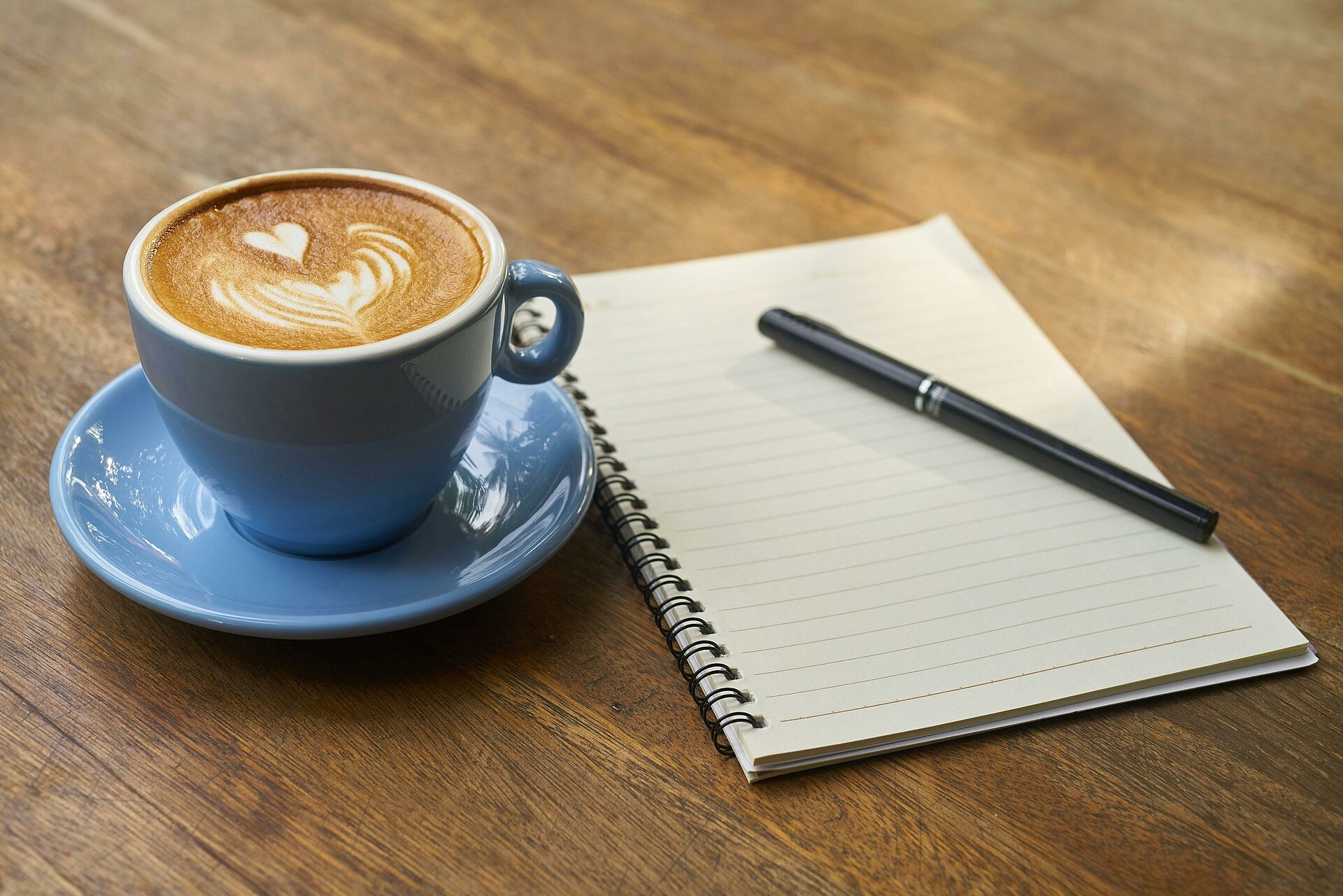 Eine Kaffee-Tasse und ein Notizheft